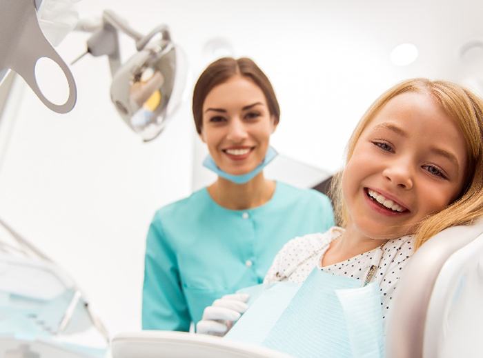 Dental assistant and child smiling at dental appointment