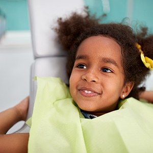 Child smiling while sitting in dentist's treatment chair