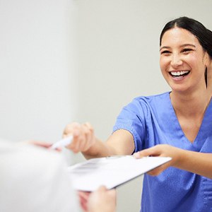 Dental assistant smiling while handing parent forms