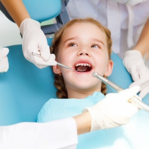 Dentist and dental assistant examining smiling child's teeth