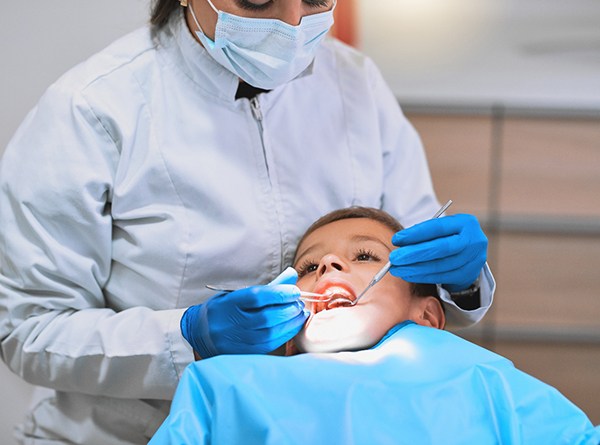 A dentist looking at a young boy’s smile