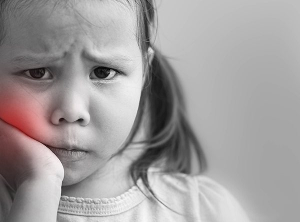 Little girl holding her cheek and frowning