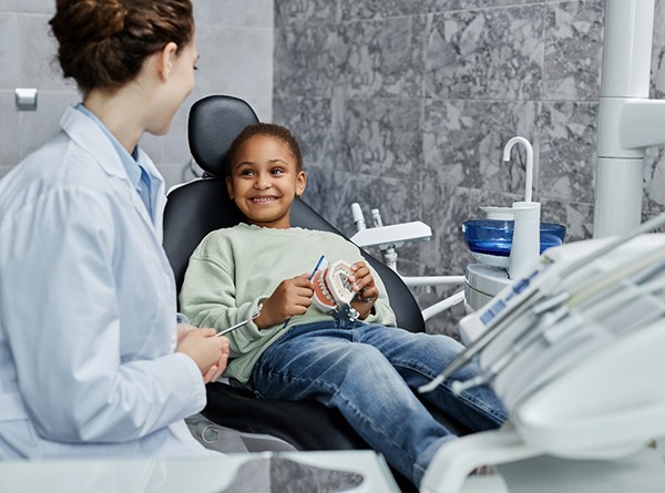 Young girl seated in the dentist’s chair and smiling