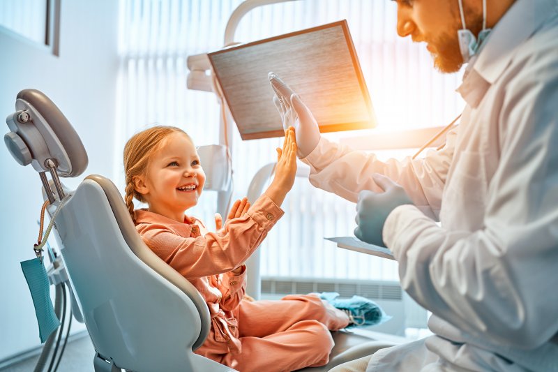 a little girl high-fiving her dentist